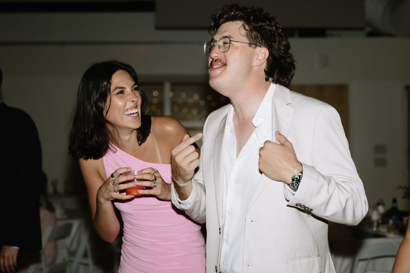 Haley and Slade laughing mid-dance-move on a wedding dance floor